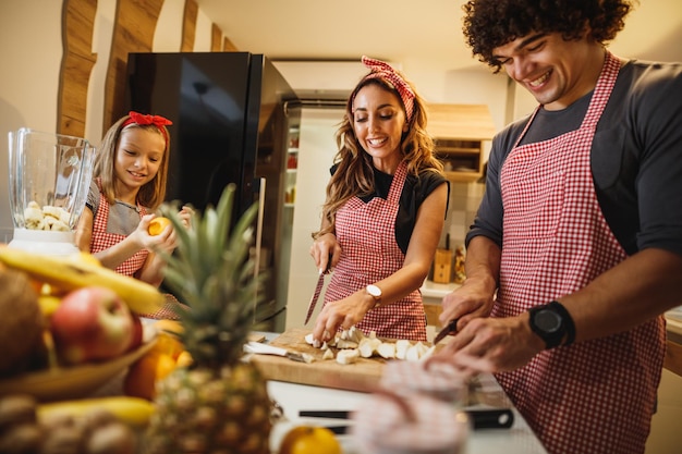 Unos padres alegres que pasan tiempo de calidad en la cocina de casa con su linda hija.