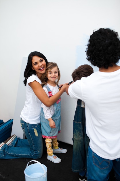 Padres alegres con sus hijos pintando una habitación