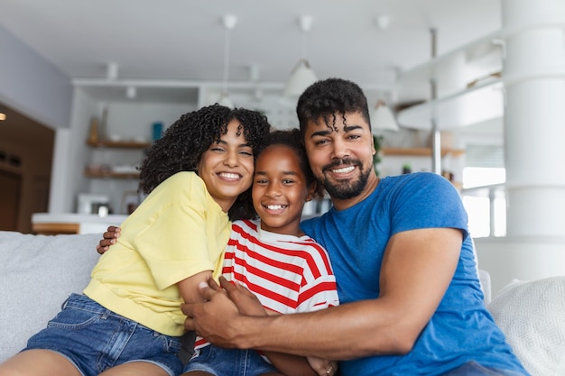 Foto padres amorosos y diversos pasan tiempo con su adorable hija, se divierten juntos en un hogar moderno, sonriendo, riendo de cerca, feliz concepto de familia multiétnica.