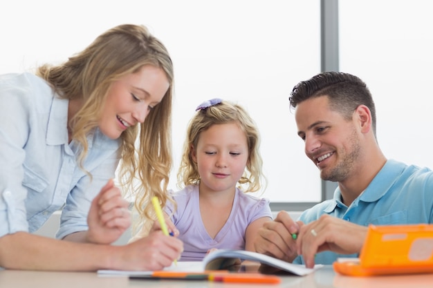 Padres ayudando a su hija a dibujar en la mesa