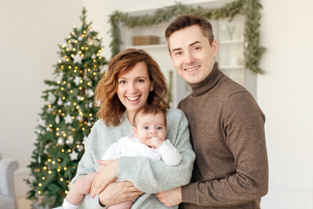Padres y bebé cerca del árbol de navidad