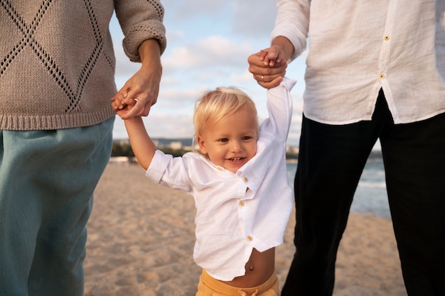 Foto padres con un bebé en la playa al atardecer