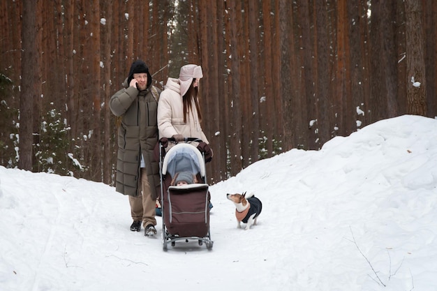 Padres caminando con bebé y perro en el bosque o parque de invierno