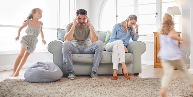 Padres dolor de cabeza correr niños y estrés familiar en la sala de estar del hogar ansiedad de niños felices y agotamiento en el salón juntos Madre y padre cansados y frustrados con jugar a las hermanas