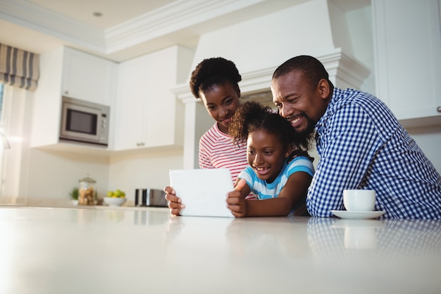 Padres e hija con tableta digital en la cocina