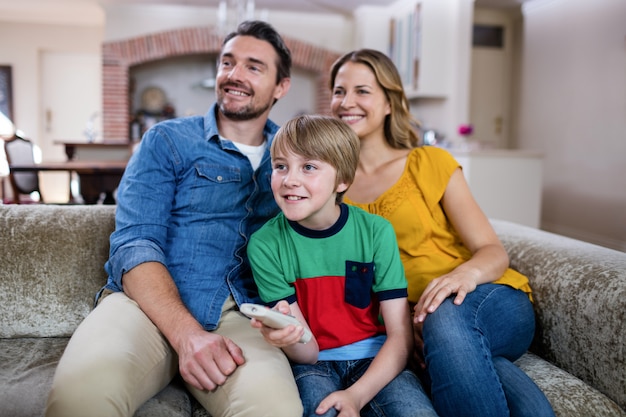 Padres e hijo mirando televisión en la sala de estar