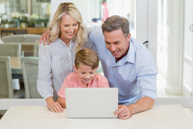 Padres e hijo usando laptop en casa