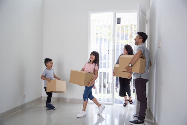 Padres e hijos con caja de cartón. mudarse a una casa nueva