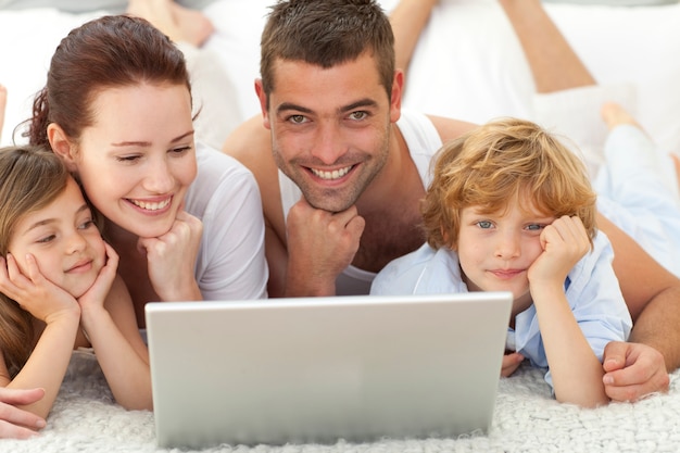 Padres e hijos en la cama usando una computadora portátil