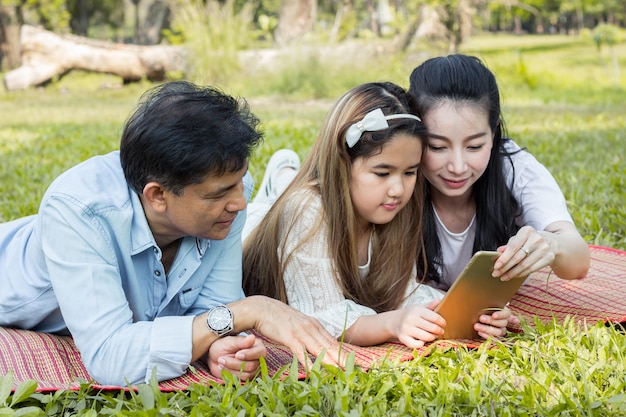 Padres e hijos están jugando la tableta en el tapete.