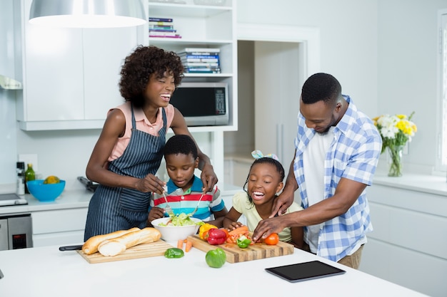 Padres e hijos preparando ensaladas en la cocina