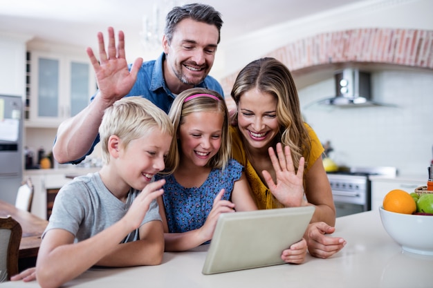 Padres e hijos saludando mientras usan tableta digital para video chat