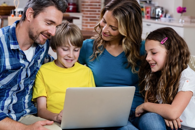 Foto padres e hijos sentados en el sofá y usando una computadora portátil