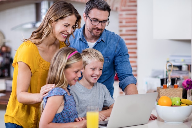 Padres e hijos usando una computadora portátil en la cocina