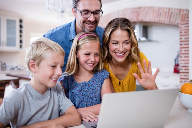 Padres e hijos usando una computadora portátil en la cocina