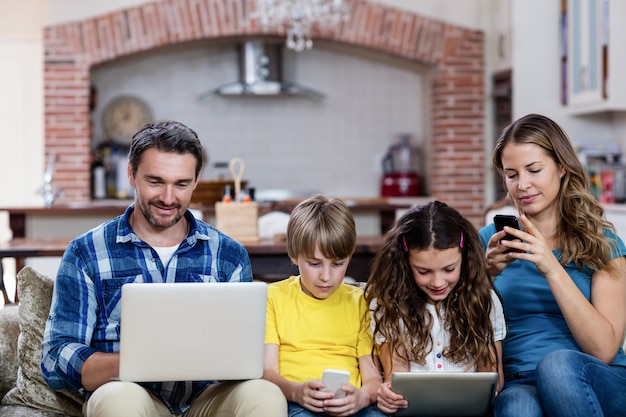 Padres e hijos usando una computadora portátil, tableta y teléfono