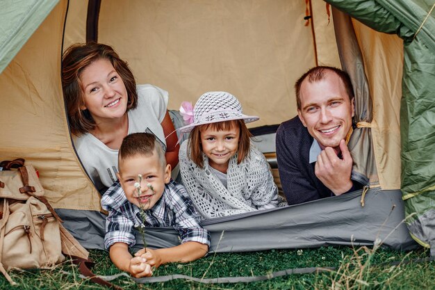 Padres de familia y dos hijos en una tienda de campaña Madre feliz padre hijo e hija en vacaciones de verano