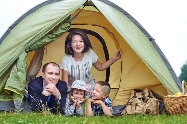 Padres de familia y dos hijos en una tienda de campaña Madre feliz padre hijo e hija en vacaciones de verano