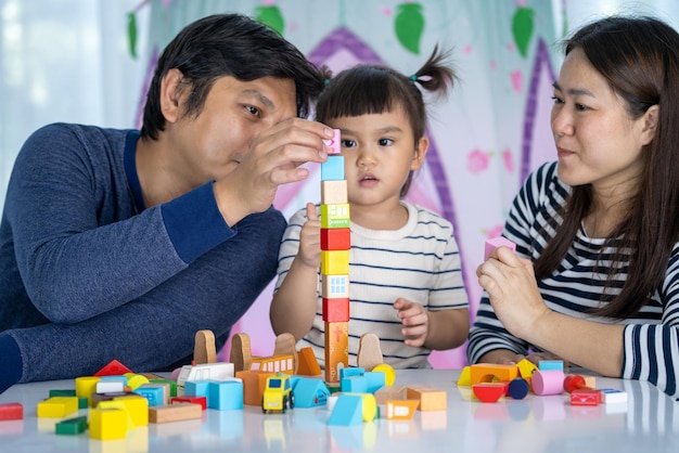 Los padres de familia felices juegan juguetes de desarrollo con su niña en el hogar dulce hogar