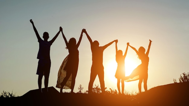 Los padres de familia felices tomados de la mano levantaron las manos hacia arriba, papá, mamá, hija e hijo son un sueño feliz en