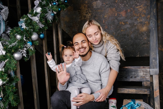 Padres felices con bebé en habitación decorada para Navidad