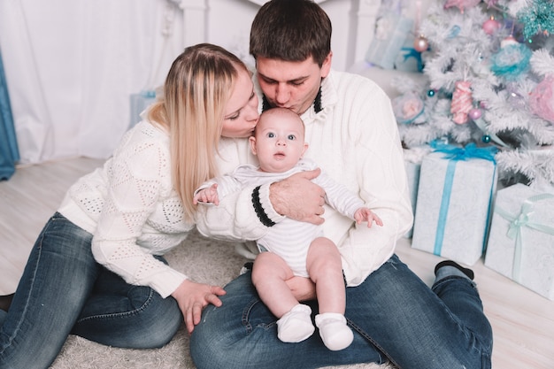 padres felices besan a su bebé en la víspera de Navidad. el concepto de felicidad