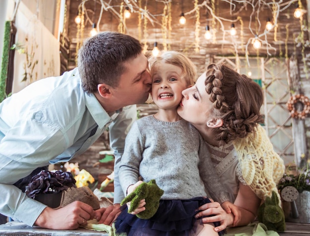 padres felices besando a su hija de cinco años