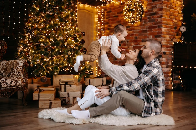 Los padres felices celebran la Navidad con su amado hijo en un hermoso ambiente acogedor en casa.