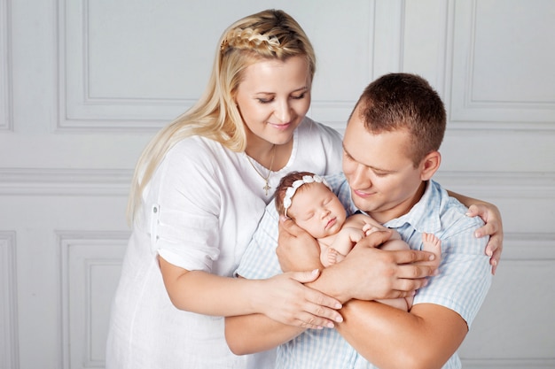 Padres felices con una linda niña recién nacida. Mamá, papá y bebé. Retrato de familia sonriente con recién nacido en las manos. Familia feliz