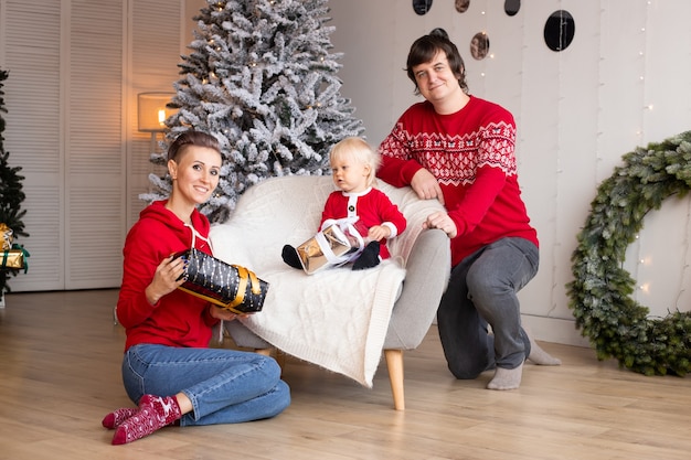 Padres felices y su pequeño hijo intercambiando regalos. Feliz Navidad y Felices Fiestas