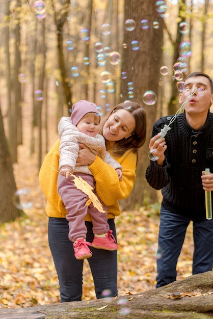 Padres con hija jugando en el bosque de otoño