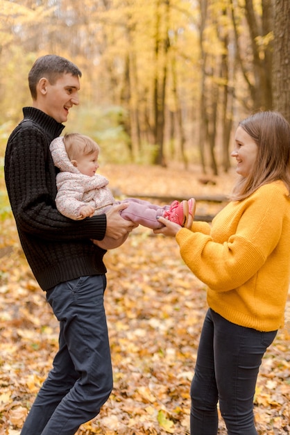 Padres con hija jugando en el bosque de otoño