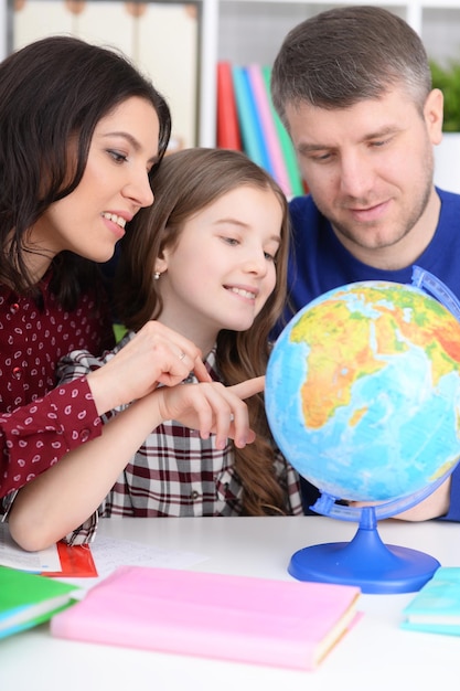 Los padres y la hija mirando el globo terráqueo en la habitación