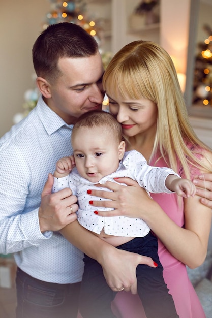 Foto los padres y el hijo son el hijo de un niño en el árbol de navidad en casa