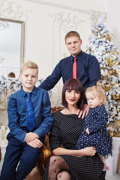 Padres con hijos cerca del árbol de Navidad.