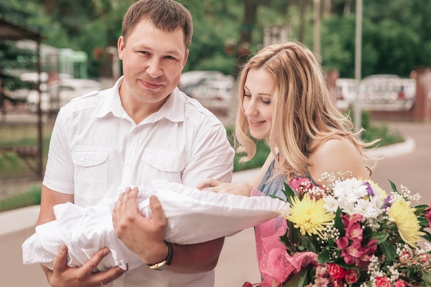 Padres jóvenes con bebé recién nacido de pie en las calles de la ciudad. el concepto de paternidad