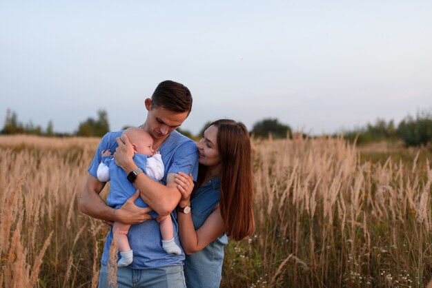 Padres jóvenes caminan con su pequeño hijo en el campo