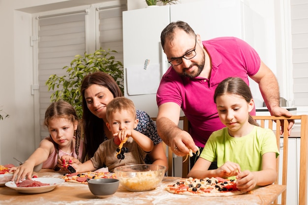 Foto los padres jóvenes están cocinando con sus hijos.