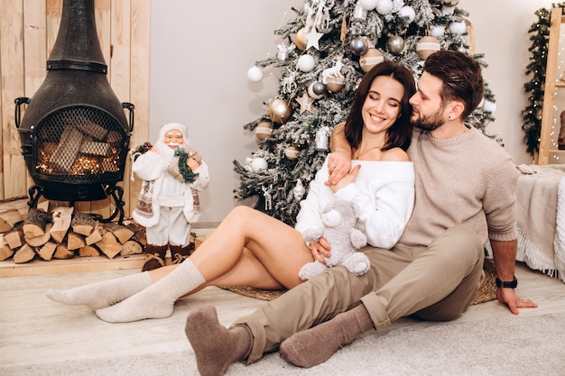 Padres jóvenes con una hija pequeña cerca del árbol de Navidad