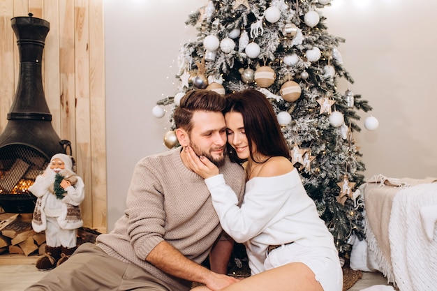 Padres jóvenes con una hija pequeña cerca del árbol de Navidad