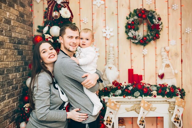 Padres jóvenes con hijo cerca del árbol de Navidad