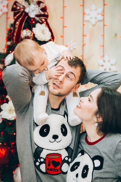 Padres jóvenes con hijo cerca del árbol de Navidad