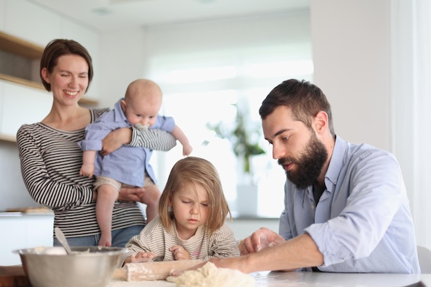 Padres jóvenes jugando con niños en la cocina