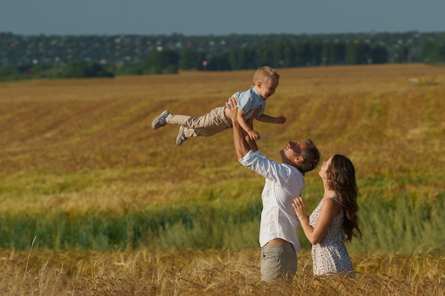 Los padres jóvenes y el niño caminando por el campo de trigo