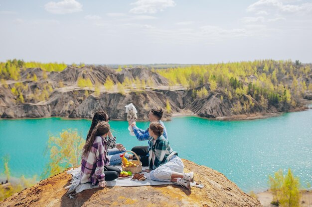 Padres jóvenes y niños en picnic después de una caminata en las montañas hermosa vista del lago azul