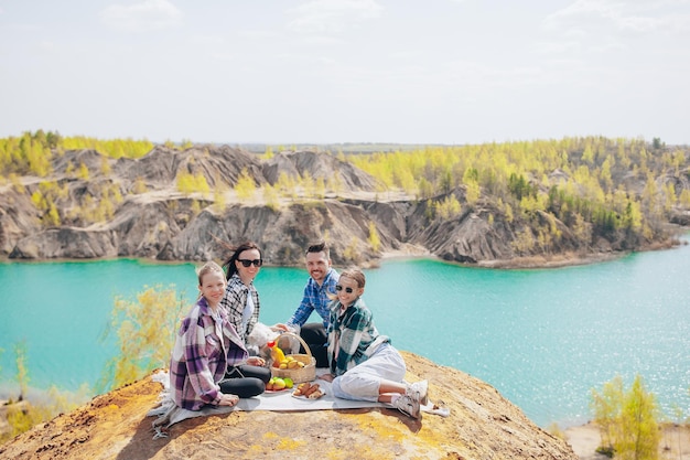 Padres jóvenes y niños en picnic después de una caminata en las montañas hermosa vista del lago azul