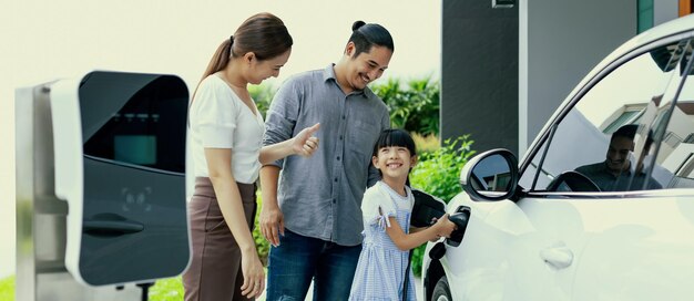 Padres jóvenes progresistas e hija que viven en una casa con un auto eléctrico