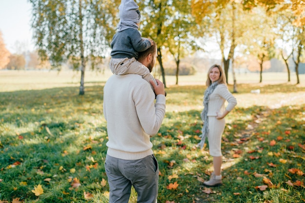 Los padres jóvenes con su bebé pasar tiempo en el parque de otoño.