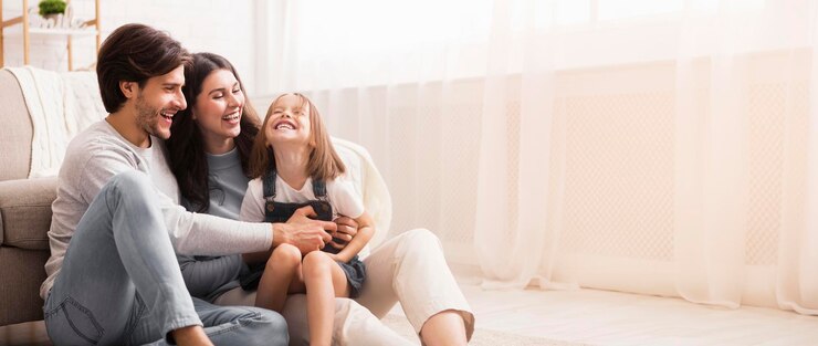 Padres juguetones que hacen cosquillas a su hija pequeña se divierten juntos en casa