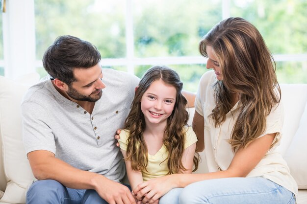 Padres mirando a la hija mientras está sentado en el sofá